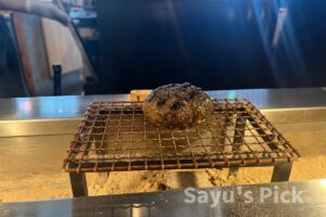 1つ目のハンバーグが網に置かれた写真です。
